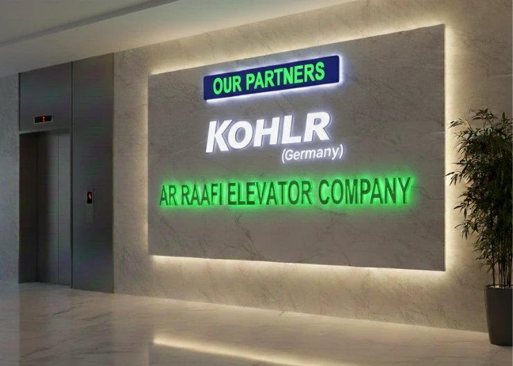 An office lobby featuring a marble wall with the "KOHLER (Germany)" logo and "AR RAAFI ELEVATOR COMPANY" in lettering under an "OUR PARTNERS" sign.